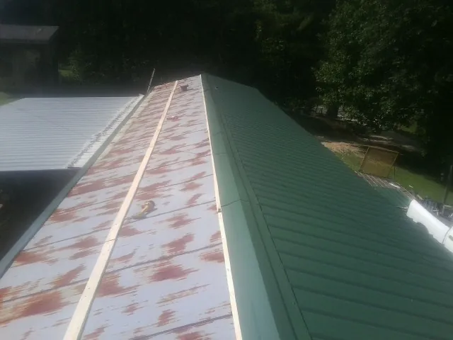 Old rusted panels beside newly installed green metal roofing — Wind Damage Roof Repair by Roofing Brothers in Bonner
