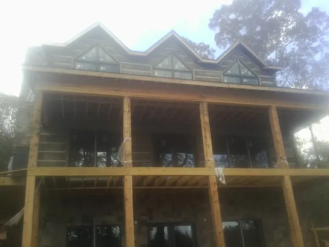 Dormers and porch framing on a large log home under construction — Roof Coating work by our crew in Bonner