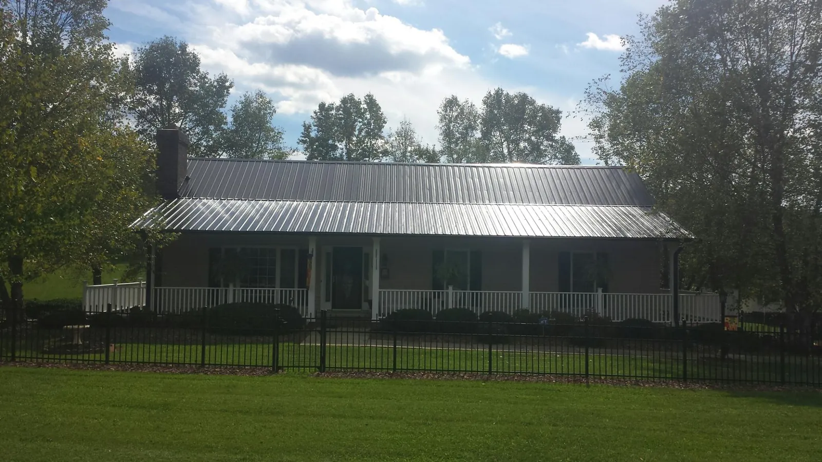 Gray metal roof on a brick ranch with a full width front porch — Gutter Guard Installation work by our crew in Bonner