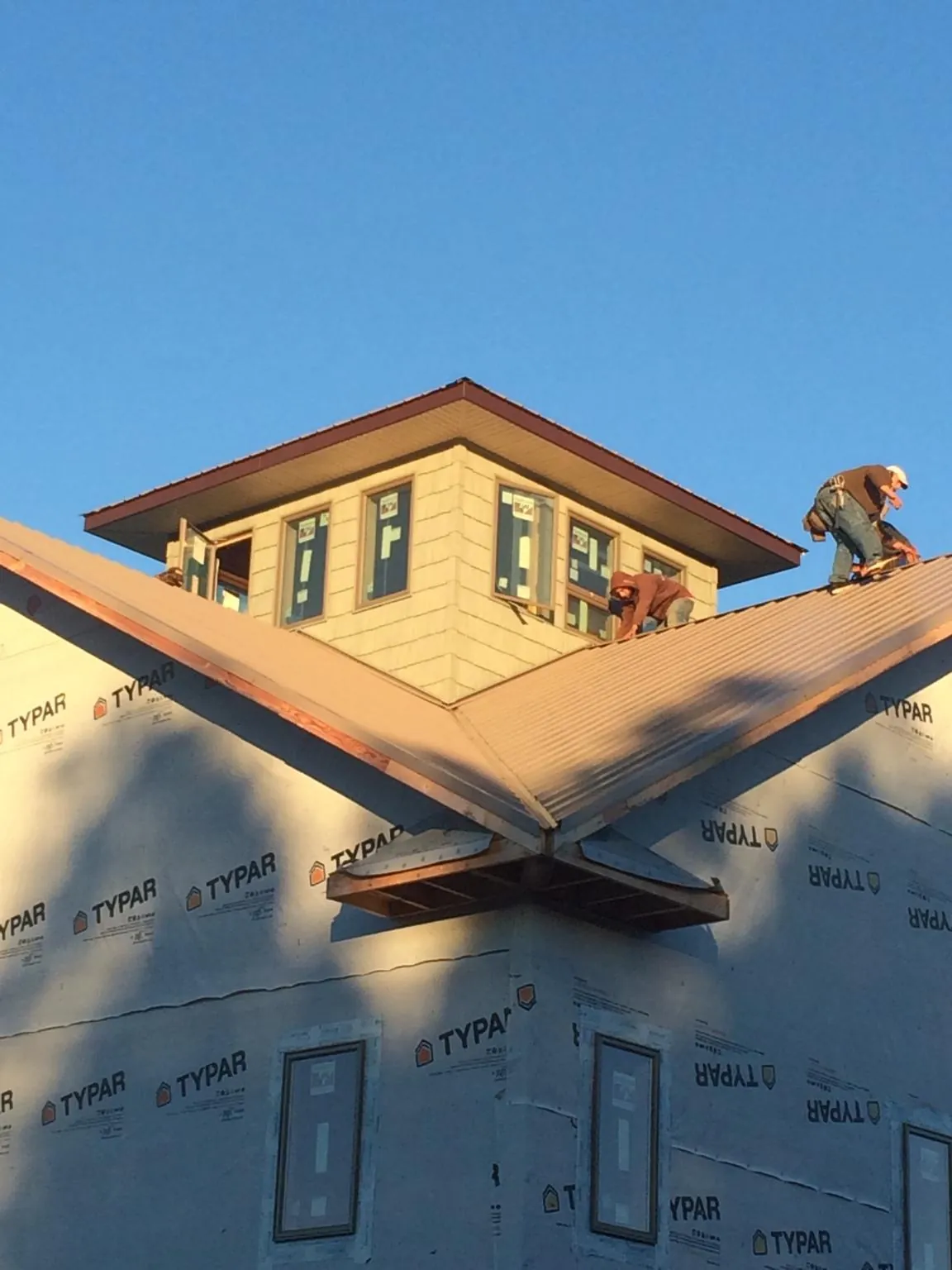 Roofers working around a rooftop cupola on a new metal roof at sunset — Roof Waterproofing in Bonner by Roofing Brothers